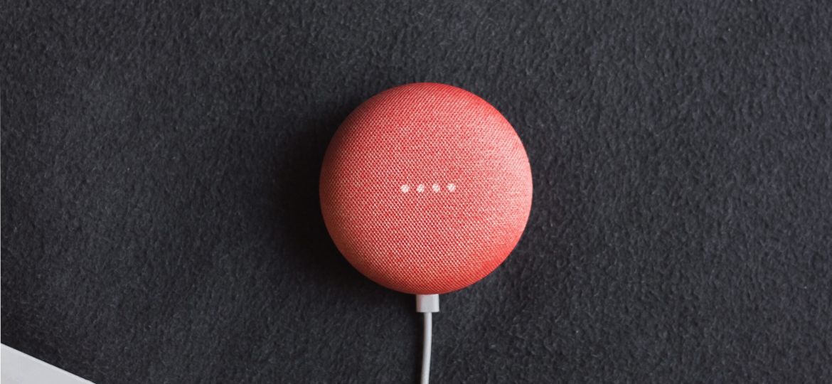 flat lay photography of coral Google Home Mini on black surface beside Apple AirPods