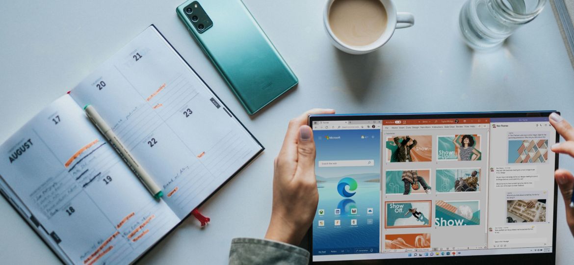 person using Windows 11 computer beside white ceramic mug on white table
