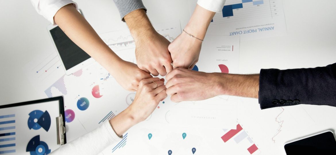 Free Colleagues celebrate success with a fist bump over financial charts depicting teamwork and unity. Stock Photo