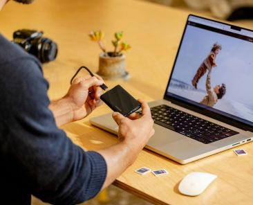 A man sitting at a table with a laptop and cell phone