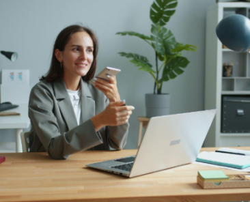lady holding phone while working on a laptop
